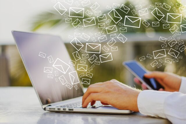 Hands typing on a computer with a phone and mail icons flying out of it, creating the perfect image for email subject lines.