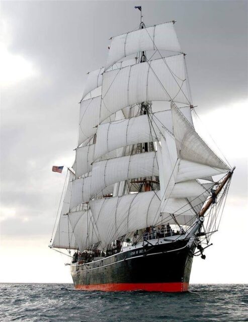 A large sailing ship with a black hull and 16 white sails.